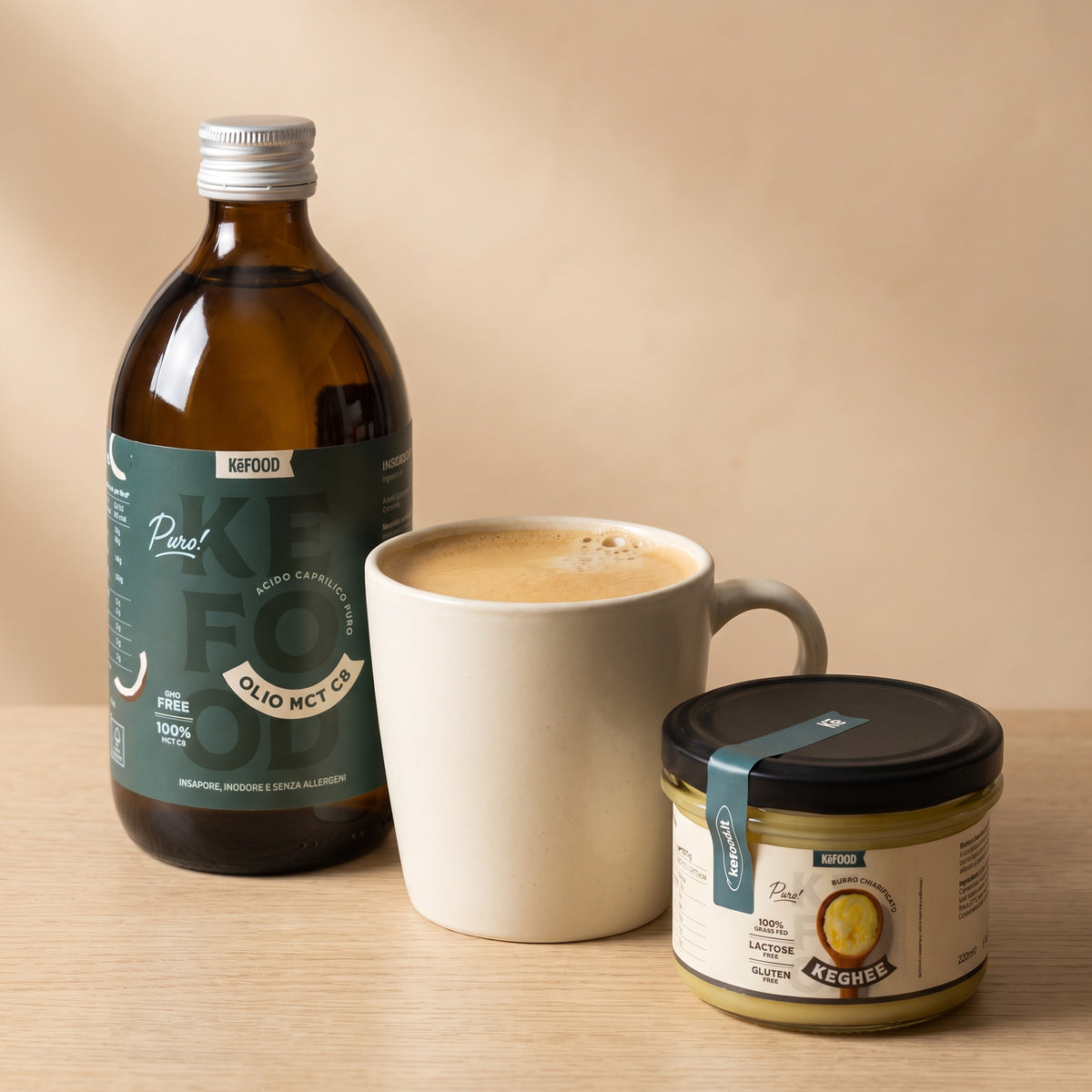 Bulletproof coffee cremoso in tazza con la bottiglia di Olio MCT C8 e il barattolo di Ghee Grass-Fed Kefood